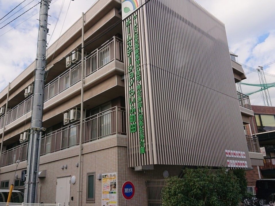 介護車両の前にいる車椅子に乗った高齢の男女と介助をするヘルパー