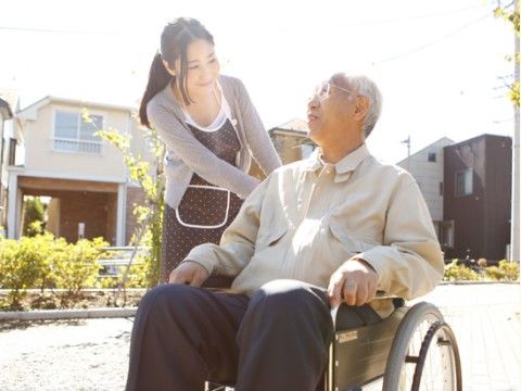 車椅子に座った入居者様の外出をサポートする介護スタッフ