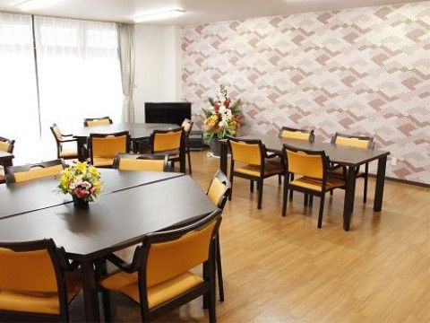 談話室にはモダンな色の椅子とテーブルが数脚並べられている。室内の壁は赤茶色の落ち着いた色を使った模様が入っており明るい印象を与える。