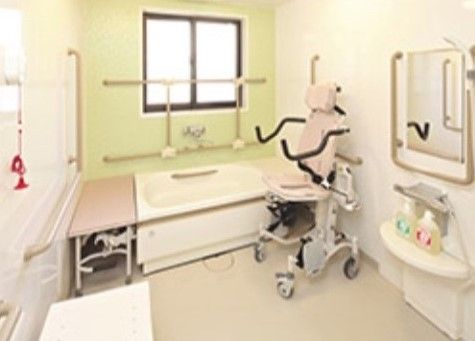 白色や薄い緑色、ピンク色など柔らかい色を使用した浴室である。介護度の高い施設入居者様が快適に利用できるように介護用の椅子を設置している。