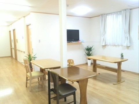 白木のフローリングが明るい雰囲気の共有スペースだ。1～2人用のテーブルと椅子がいくつか置かれている。テレビも設置されている。