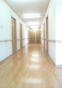 淡い色調のフローリングが柔らかい印象の廊下である。バリアフリー設計で広々としていて車椅子をご利用の方でも移動しやすい。