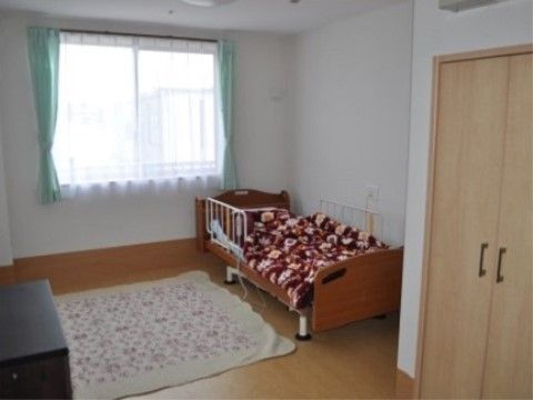 清潔感のある白い壁紙と、落ち着いた色合いのフローリングの居室。大きな窓があり明るさも十分に確保されている。