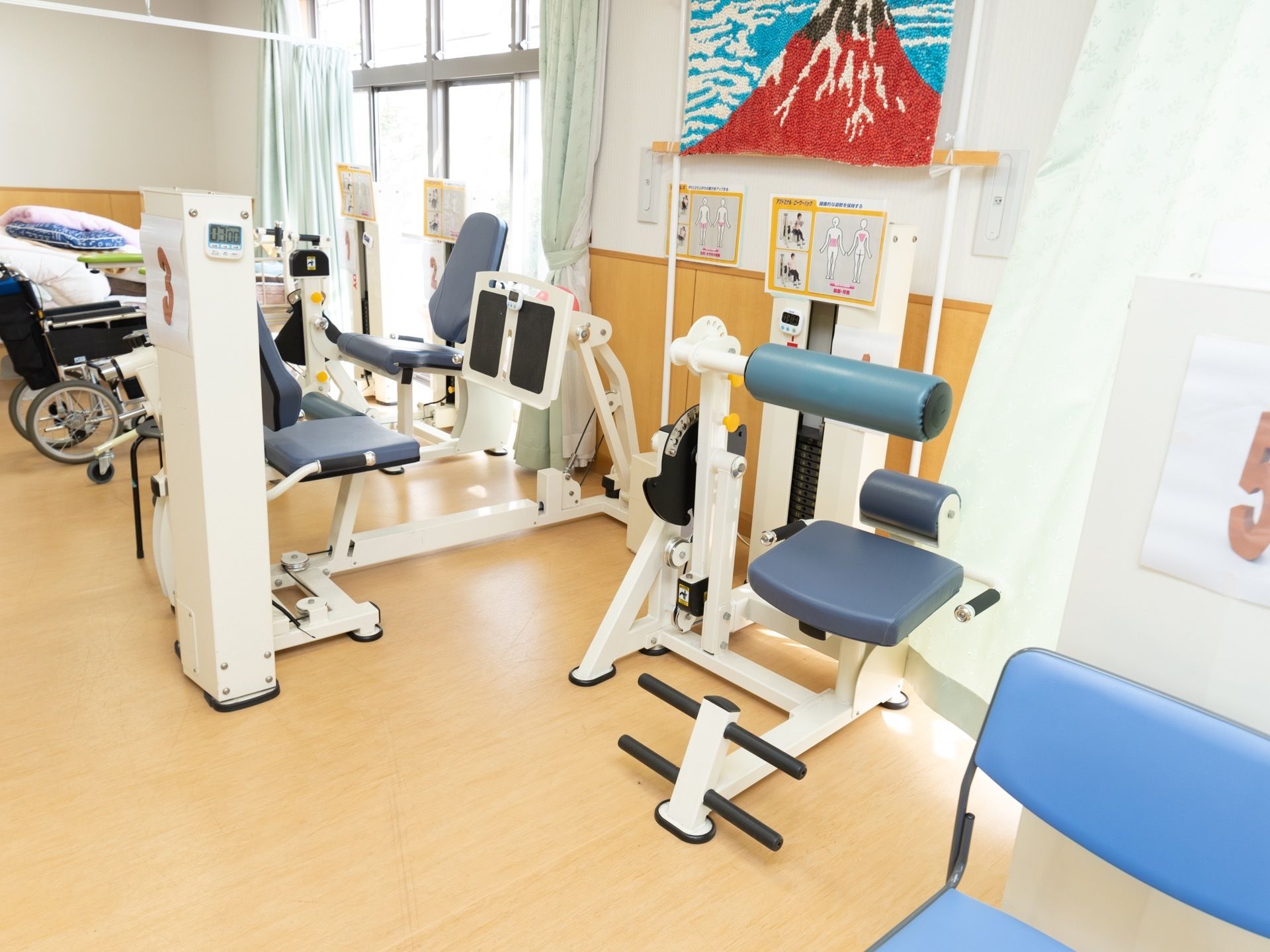運動器具が並んだ部屋である。壁には使用方法についての写真が貼られている。さらに富士山の絵が飾られている。