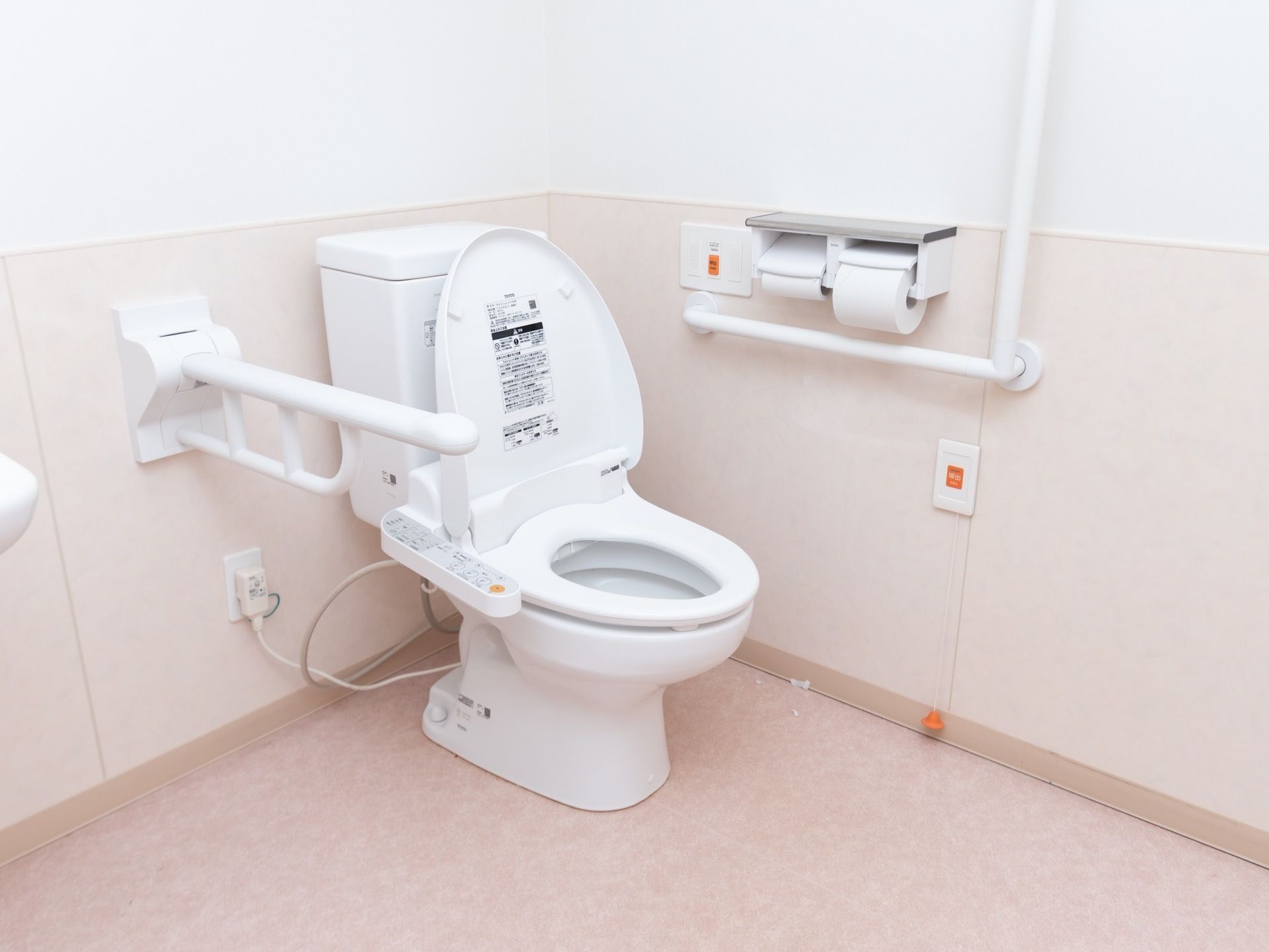 可動式の手すりや、緊急時呼び出しボタンが備わった広いトイレである。呼び出しボタンから出ているひもは床上まで伸びている。