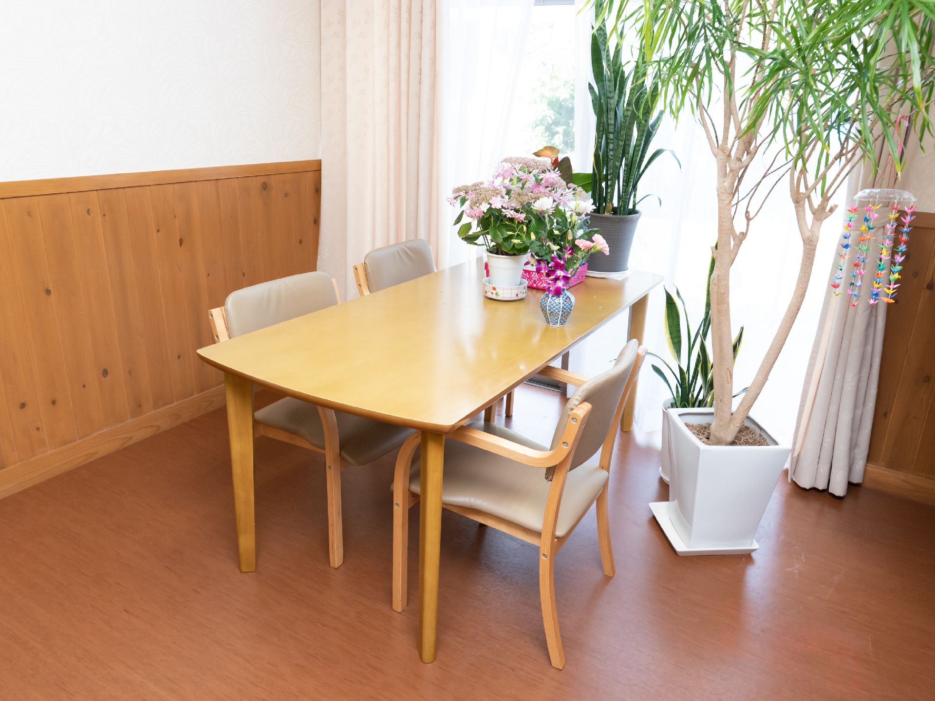 窓際のテーブルに花や観葉植物を置いて、親しみやすい雰囲気を演出した共有スペース
