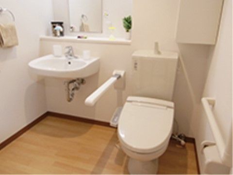 「いせはら療養センター」の洗面台・トイレ。可倒式の手すりとフットレスの洗面台を施している。