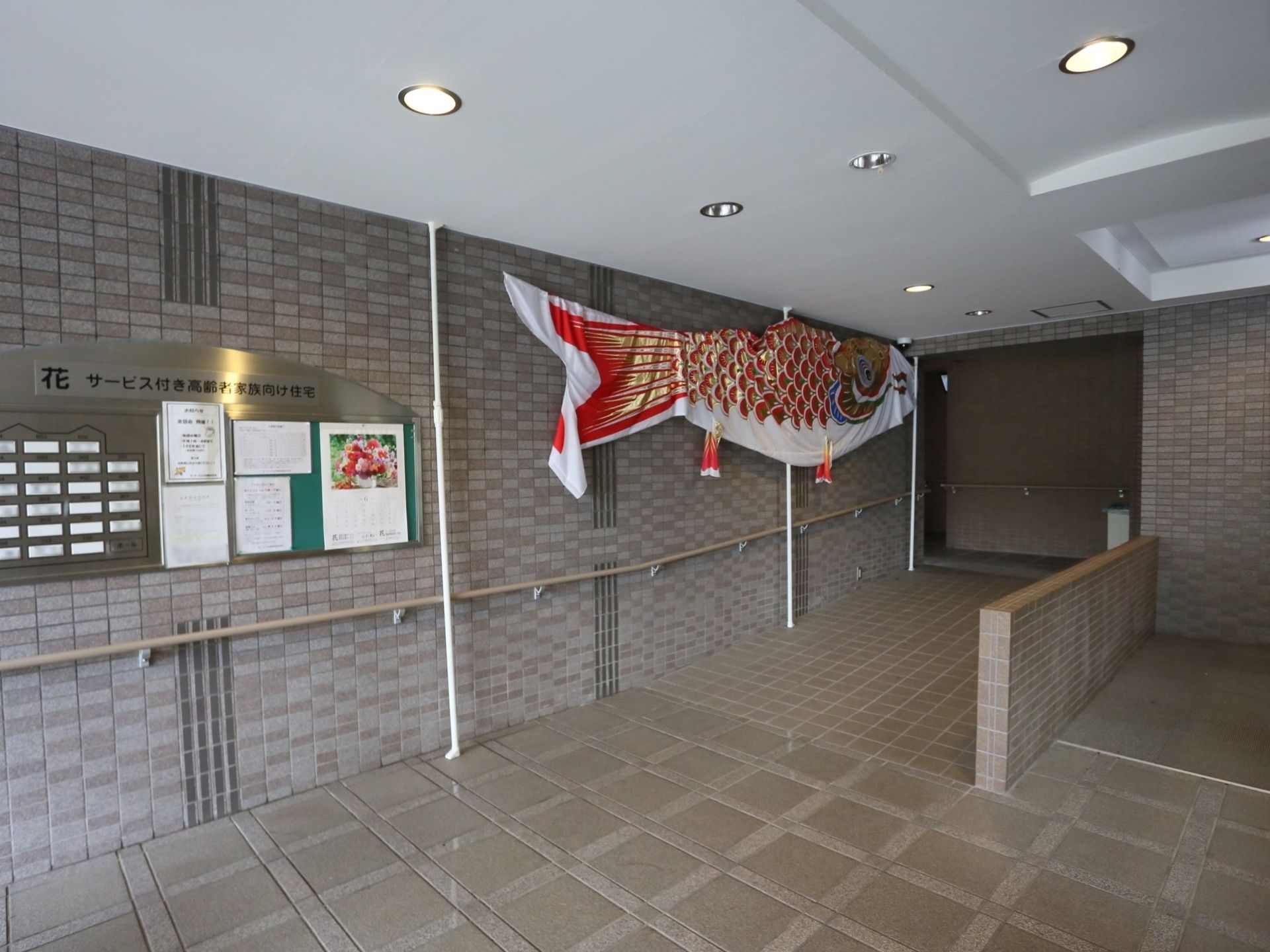 レンガ調の壁とタイル調の床面で統一された施設の入口である。壁には手すりが備え付けられているほか、床の一部は緩やかなスロープとなっている。