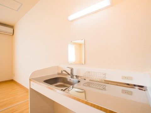 清潔感のあるキッチンである。壁には鏡が設置されているため、入居者様は歯ミガキや身だしなみを整えることもできる。