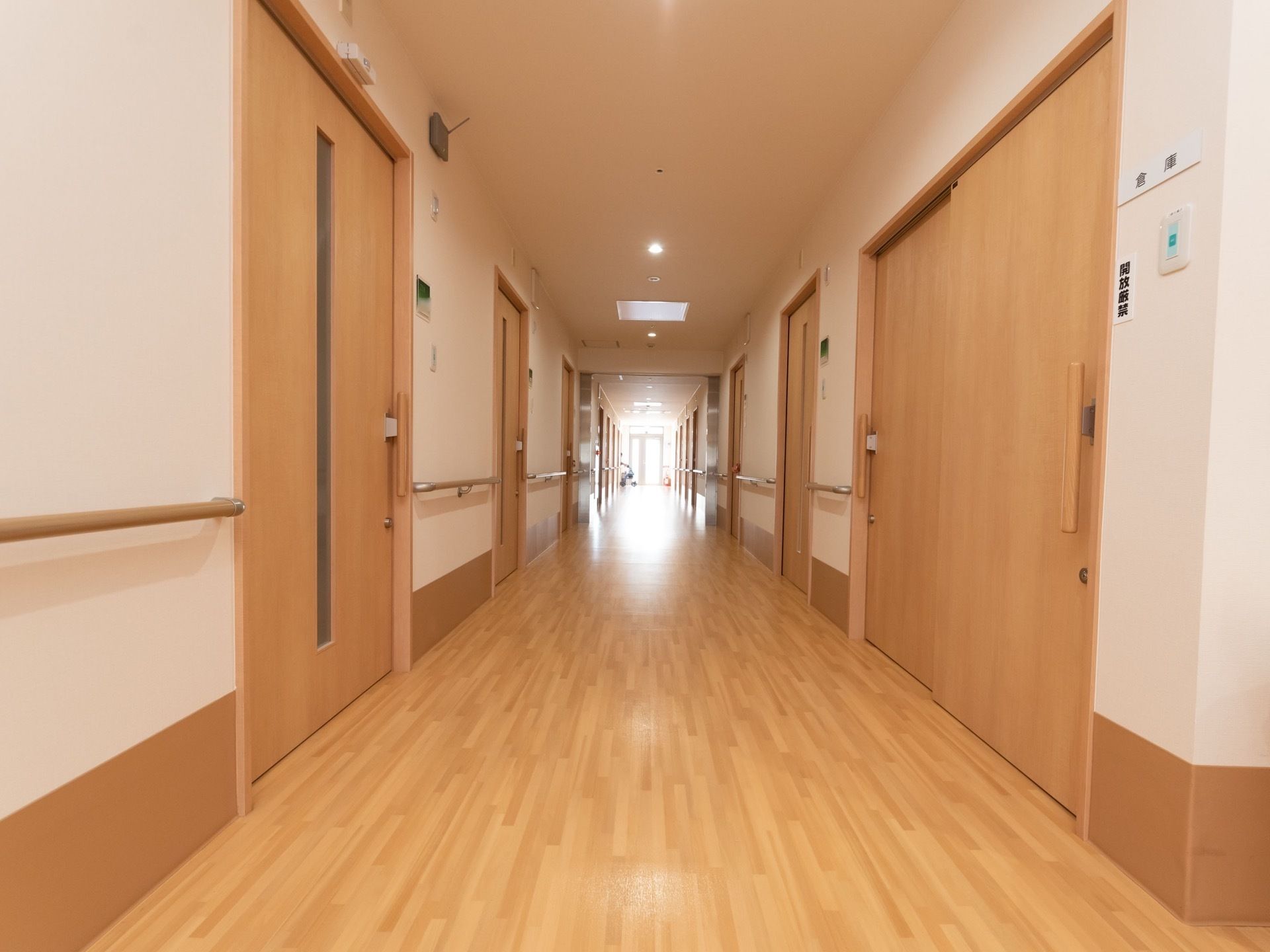 ライトブラウンと白でまとめられた上品なデザインの通路である。右端には倉庫があり、開放厳禁と書かれたパネルが見える。