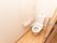 白と木目調デザインで統一されたシンプルな内装のトイレである。左側にペーパーホルダーが２つあり、その上に手すりもある。