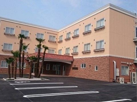 施設は３階建ての建物である。広々とした駐車場が建物前に設けられている。エントランスの目の前には、シュロ木が植えられている。