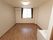 突き当たりに窓のついた洋室がある。左側の壁はチェック柄の壁紙が使われている。窓の横にはエアコンが設置されている。