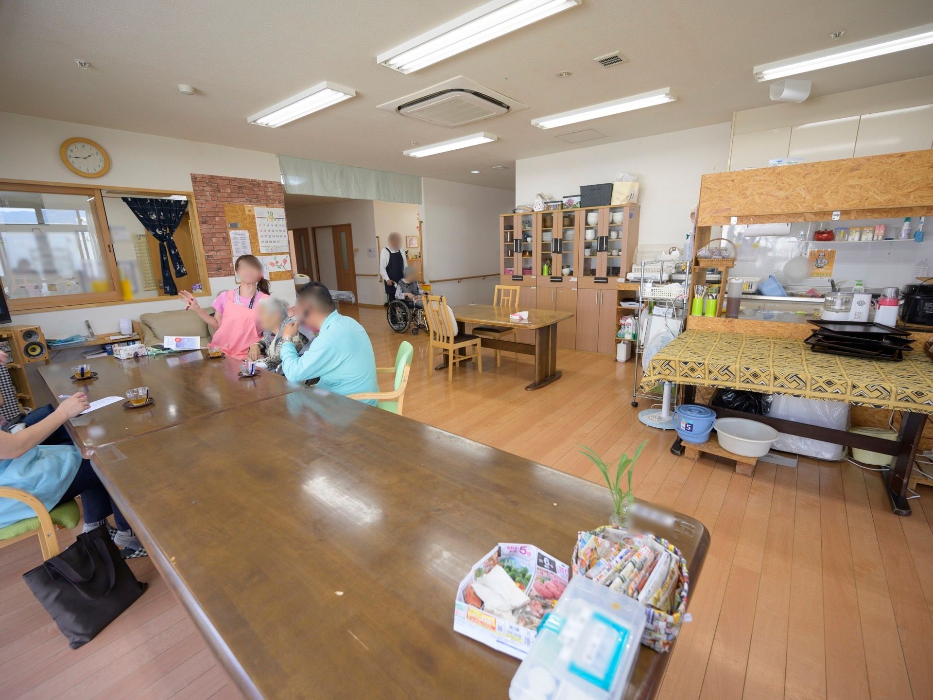 ダイニングテーブルが数カ所に置かれたフロアがある。スタッフと入居者様が席について、お茶を飲みながら談笑している。