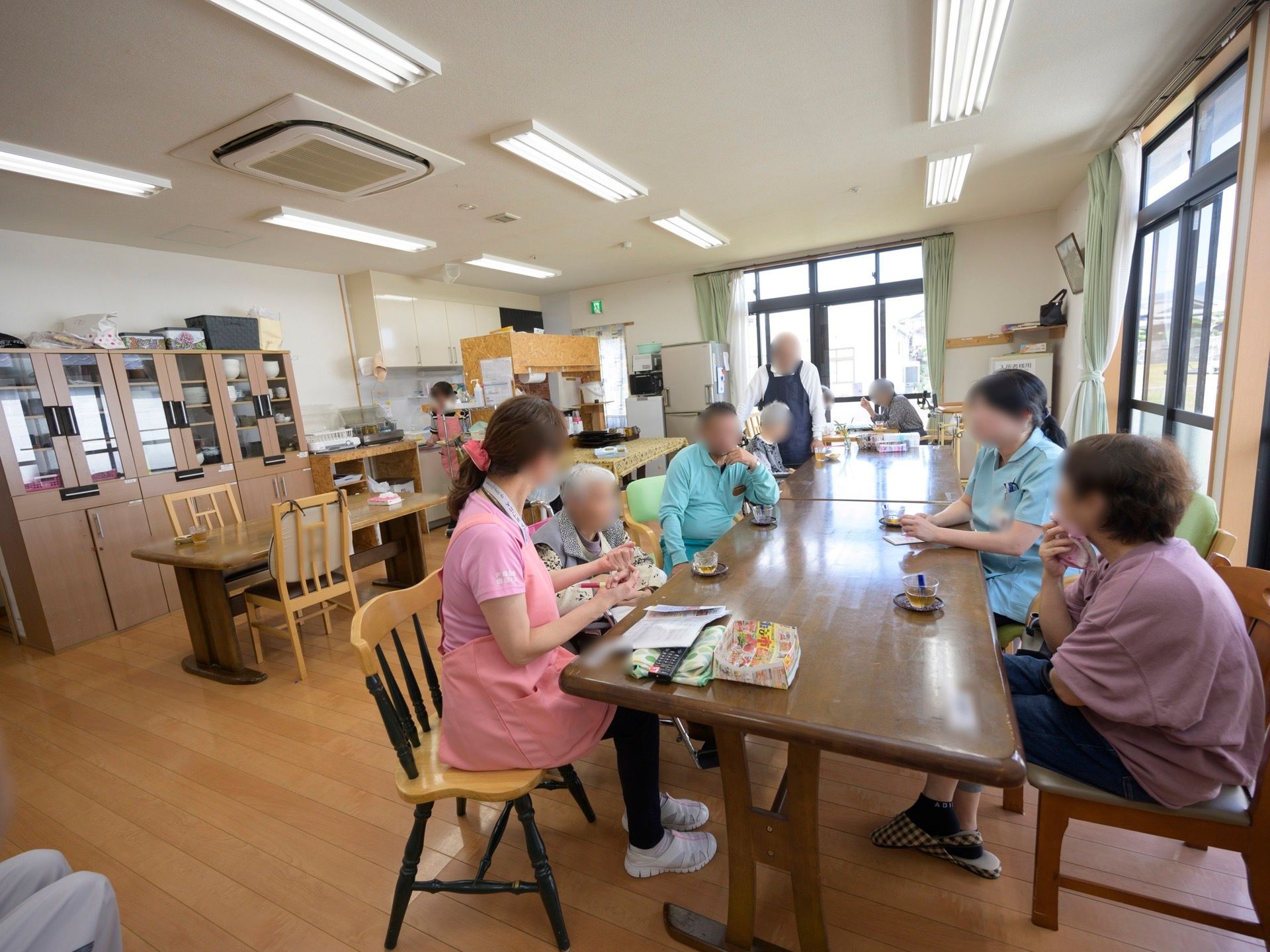 フローリングの広々としたスペースがある。奥にはキッチンがあり、壁際には冷蔵庫や食器棚が設置されている。