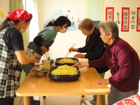 ホットプレートでスタッフと一緒に焼きそばを作る２人の女性