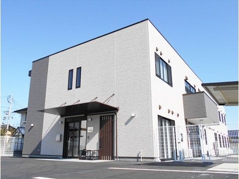 敷地内に駐車場のある、白を基調とした２階建ての住宅