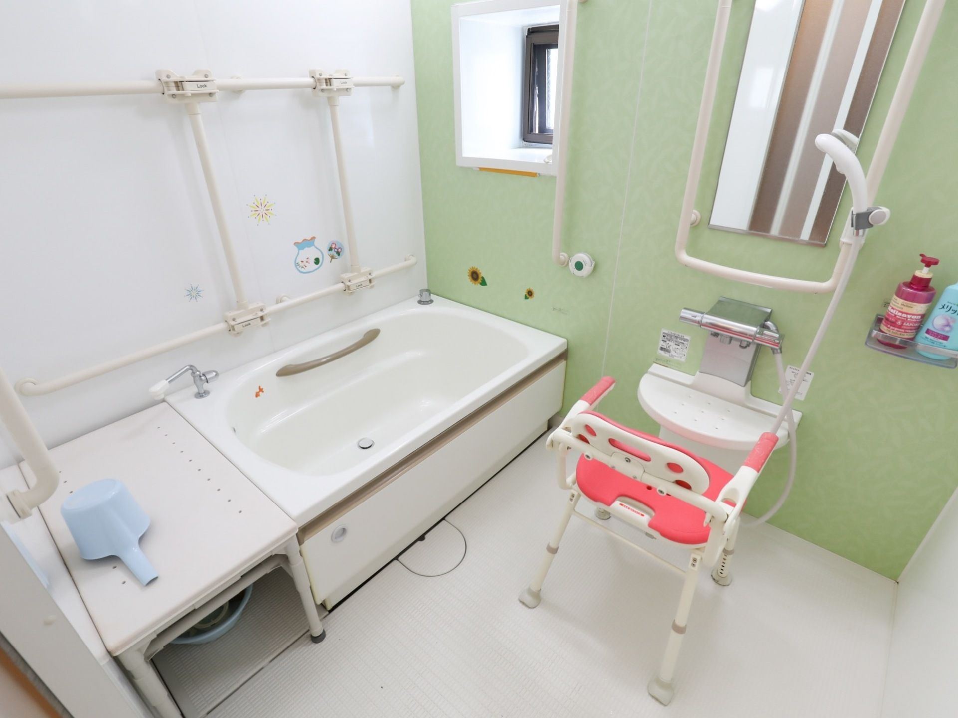 シャワーチェアが置かれている。洗い場のカウンターにはシャンプーとボディーソープが用意されている。シャワーは高さ調整ができるようになっている。
