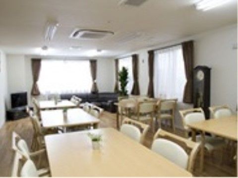 広々としたゆとりのある食堂に、テーブルと椅子が並べられている。奥にはくつろぎ用のソファーが配置されている。