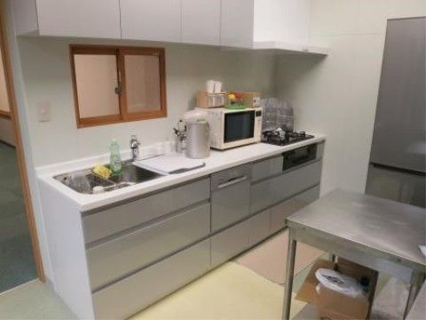 キッチン台に洗い場とまな板を置くスペースのほか、電気ケトルやレンジ、奥にはコンロ三口とグリルが設置されている。