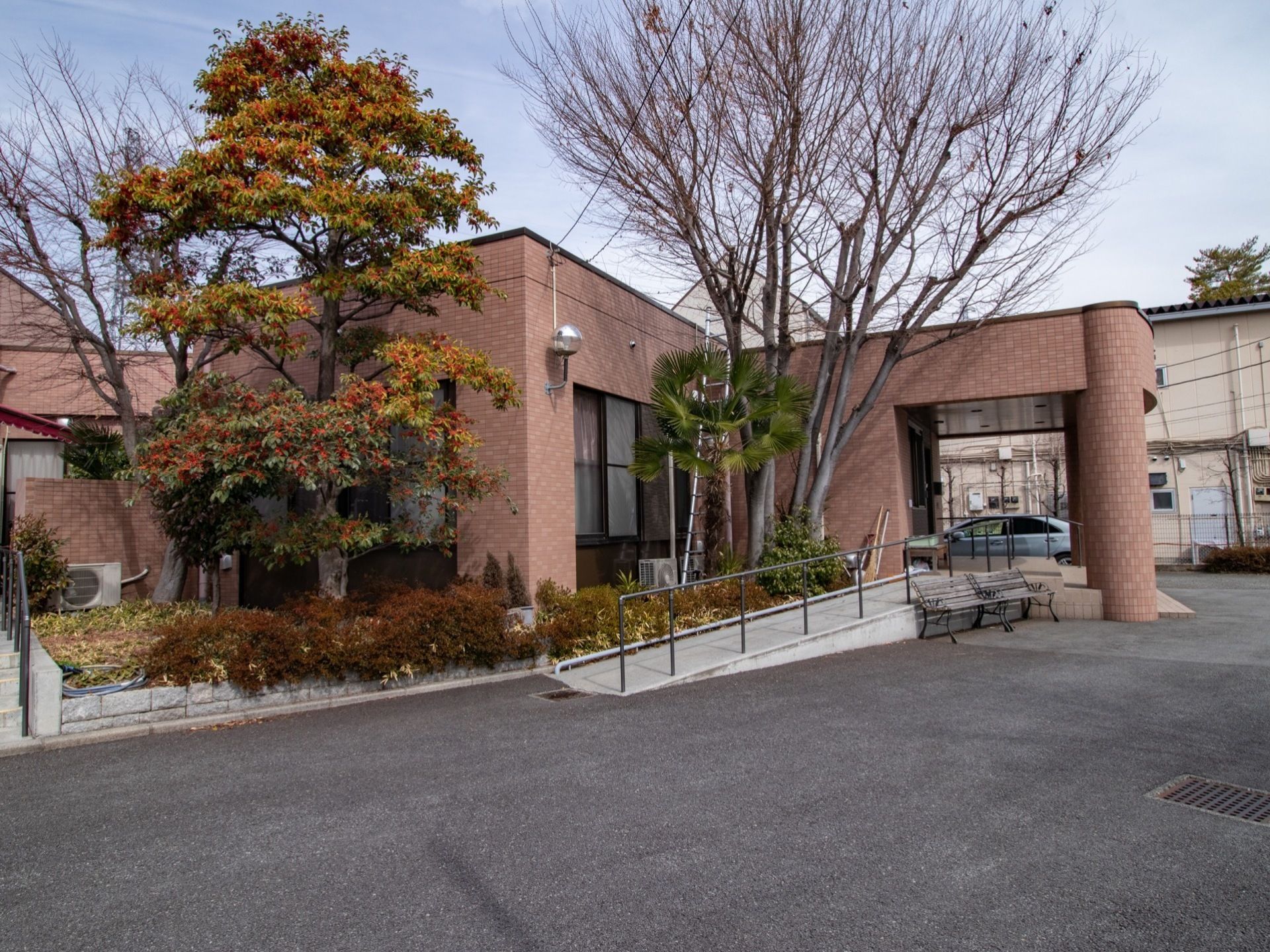 レンガ調のあたたかみのある施設外観である。さまざまな種類の植栽が施されており、１階部分の外からの目隠しとなっている。