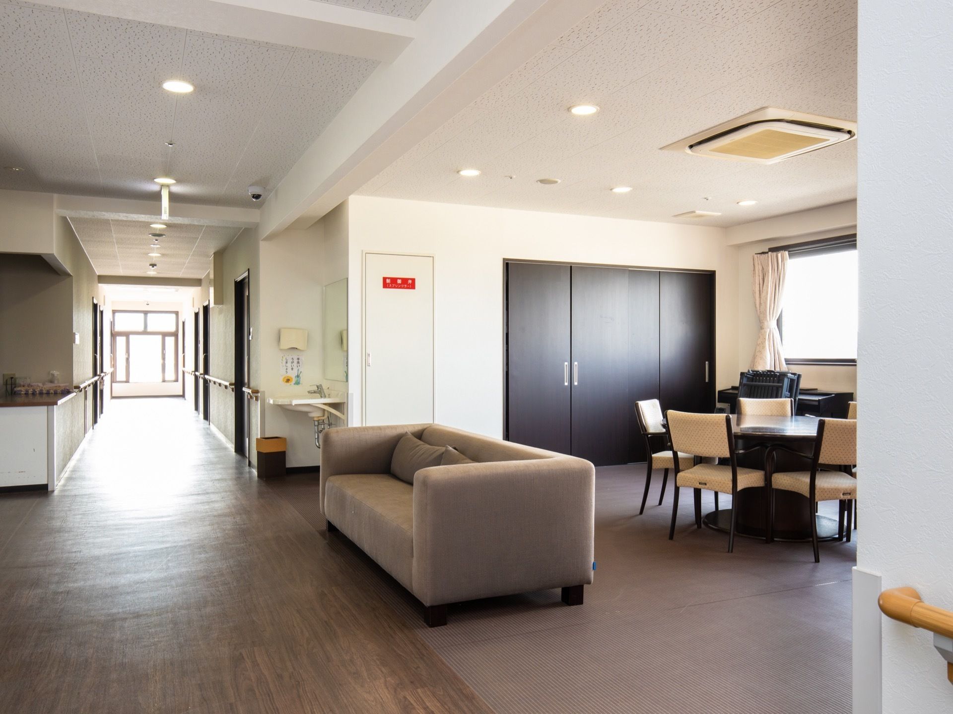 通路脇の一角が広くなっていて、円形のテーブルが置かれ、それを囲むように椅子が配置されている。手前には布張りのソファがある。