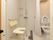 居室のシャワールームである。シャワーカーテンを隔ててトイレが設置されている。壁には手すりがあり、シャワー正面には椅子が置かれている。