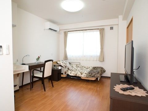 テレビやデスク、ベッドなどの家具が置かれたワンルーム