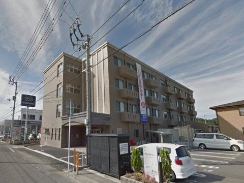 建物横に駐車スペースを設けている。車を停めやすいように白線を引いている。出入口の傍に緑の植栽の花壇を設け看板を掲げている。