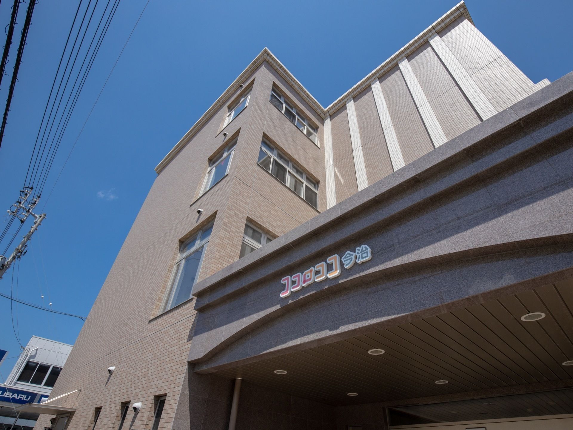 ホテルのような４階建ての建物がある。壁はタイルで覆われていて、玄関部分は屋根付きのポーチになっている。