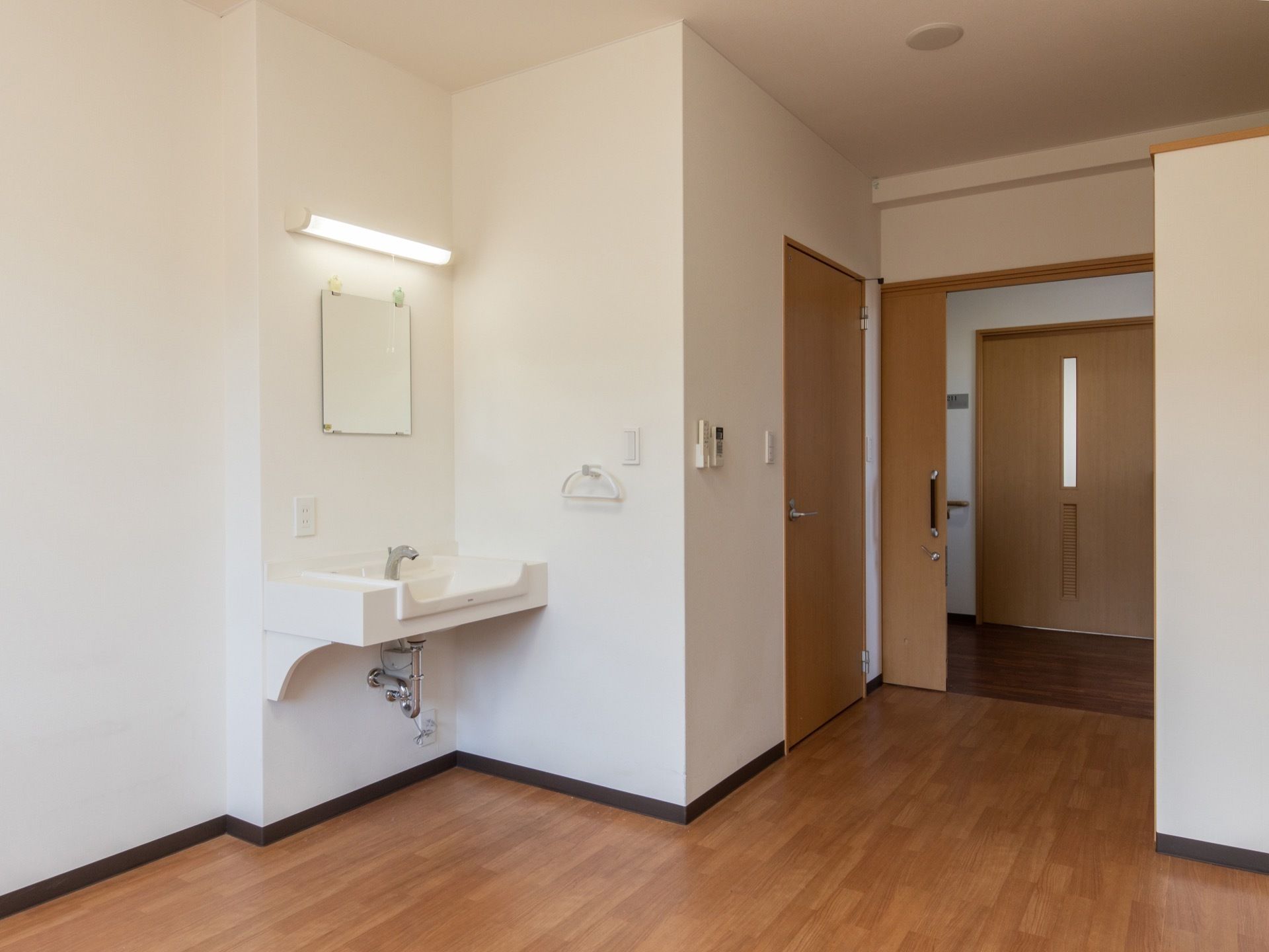 木製の引き戸を入ると、フローリングの部屋が広がっている。壁際には洗面台があり、鏡と照明がついている。