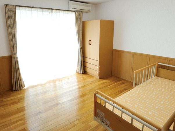 収納ダンスとベッドが置かれた、大きな窓のあるワンルーム