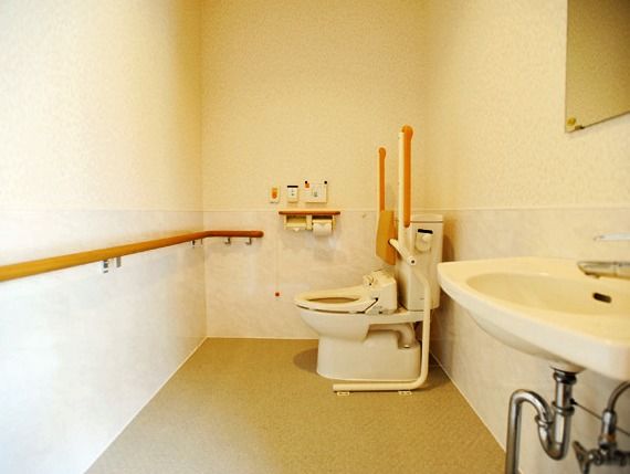トイレは温水洗浄便座を用意している。壁には操作用のパネルと非常ボタンが取り付けられ、便座には折り畳み式の手すりがある。