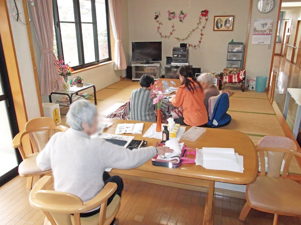 こたつで女性入居者様と子どもが遊んでいる、小上がりの畳スペース