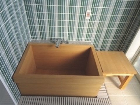 檜風呂が完備されている浴室では、壁に呼び出しブザーが設置されている。置かれている入浴補助台も檜造りである。