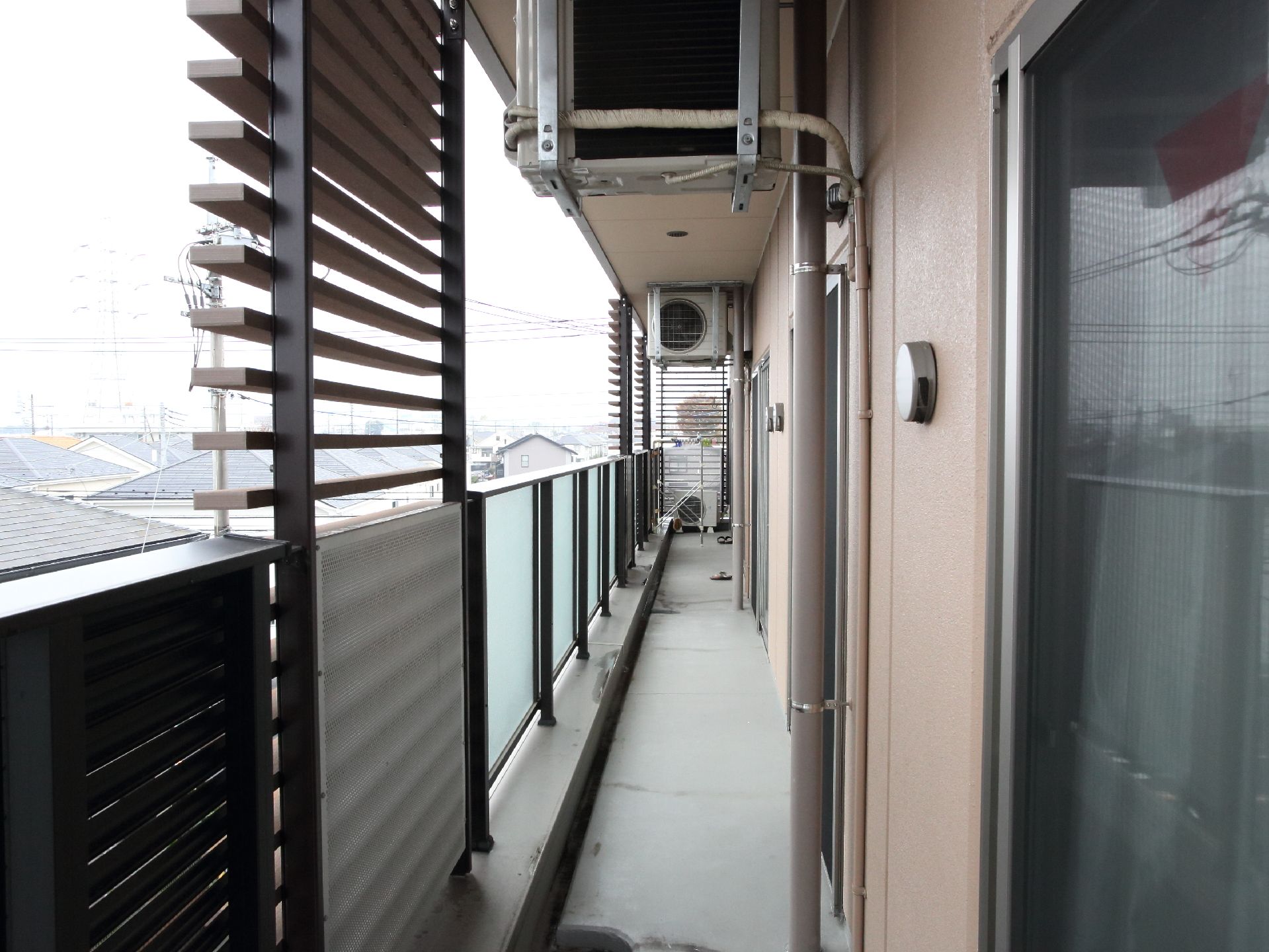 個室にはベランダがあり、外の景色や空をを眺めることができる。上部には各部屋のエアコン室外機が設置されている。