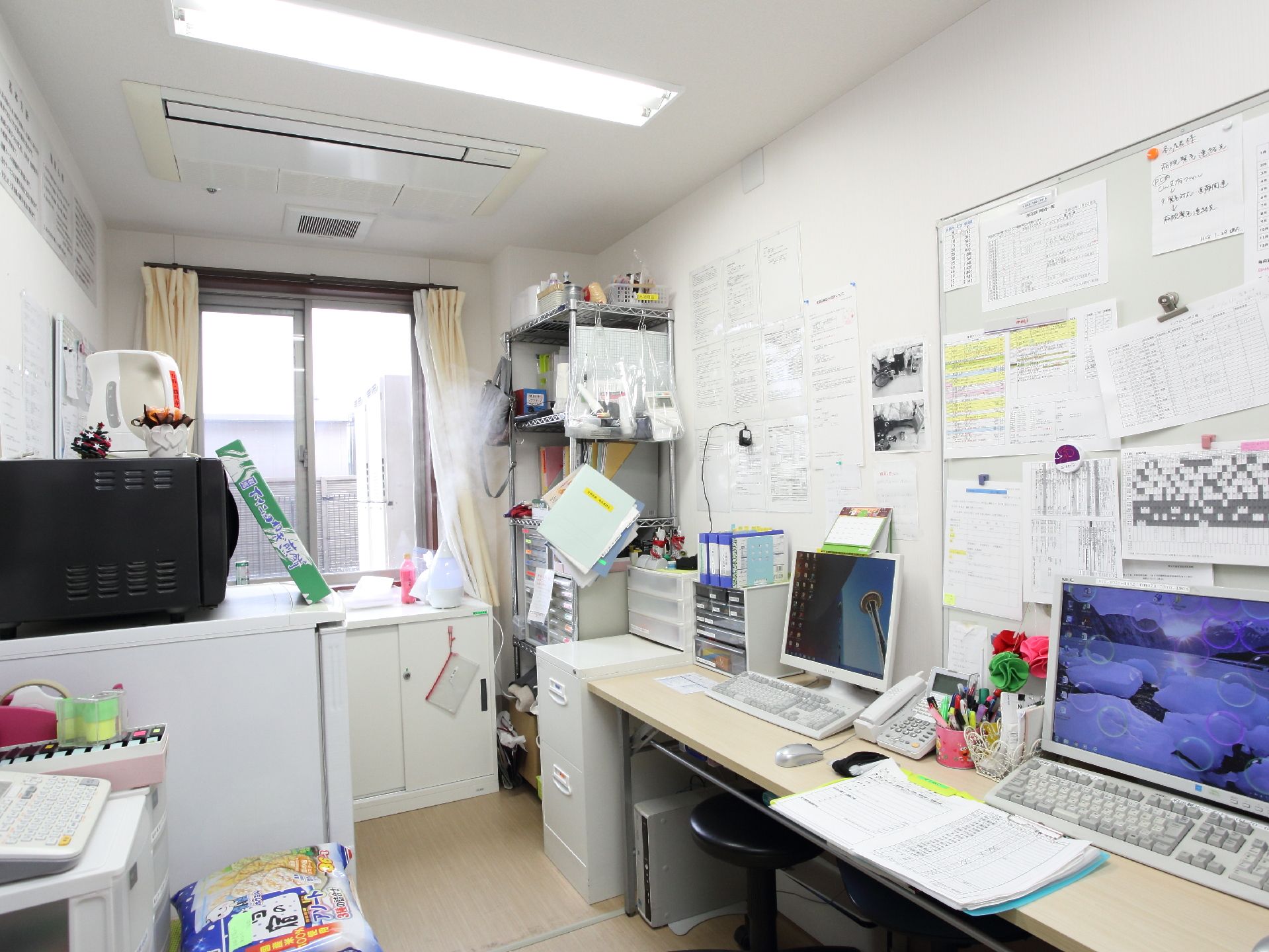 スタッフの休憩所、事務処理をする部屋では、スケジュール管理、ホワイトボードにはたくさんの書類が提示されている。