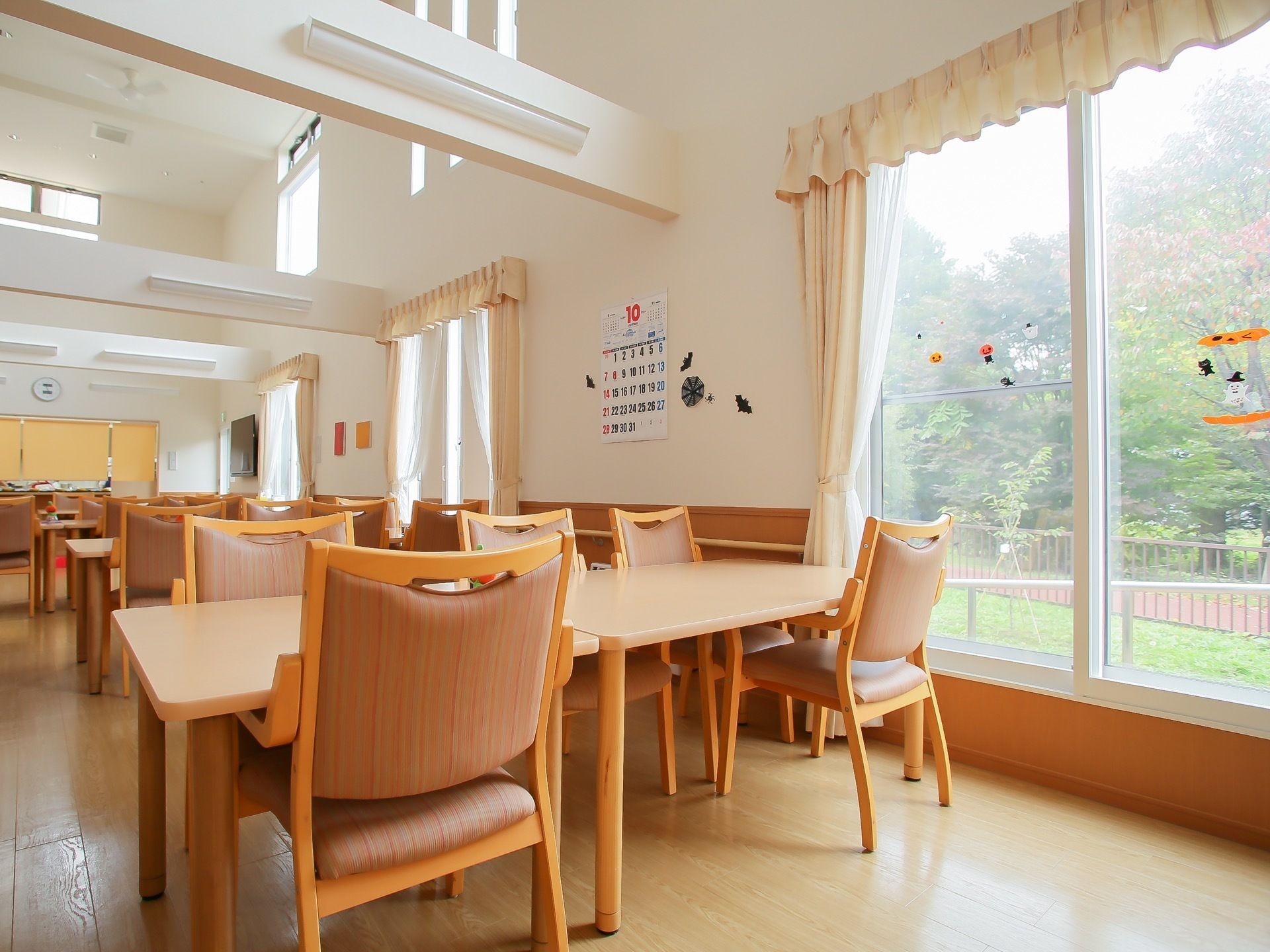 広々としたあたたかい雰囲気の食堂である。ダイニングテーブルが並べられており、散策路を望める窓がある。天井は吹き抜けになっている。