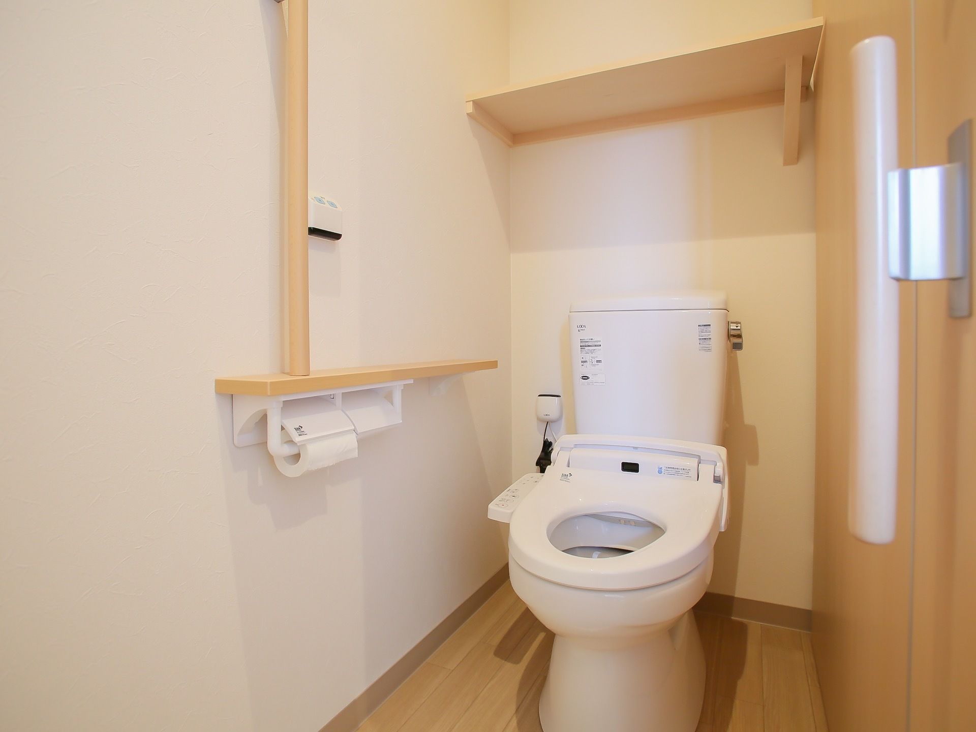 白を基調とした、シンプルなトイレである。温水洗浄便座が完備されている。上部には木製の板が備えつけられている。