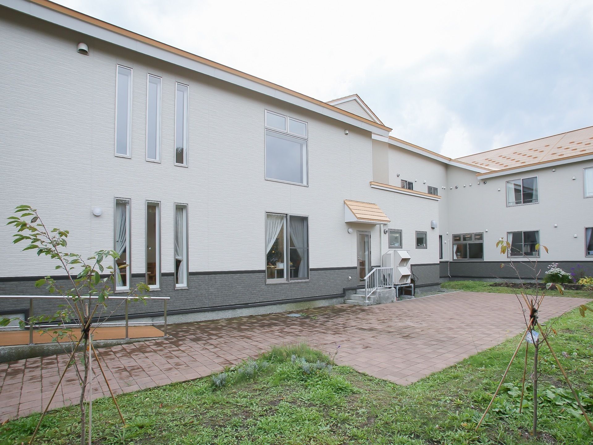 白を基調とした２階建てのグループホームと、敷地内にある中庭