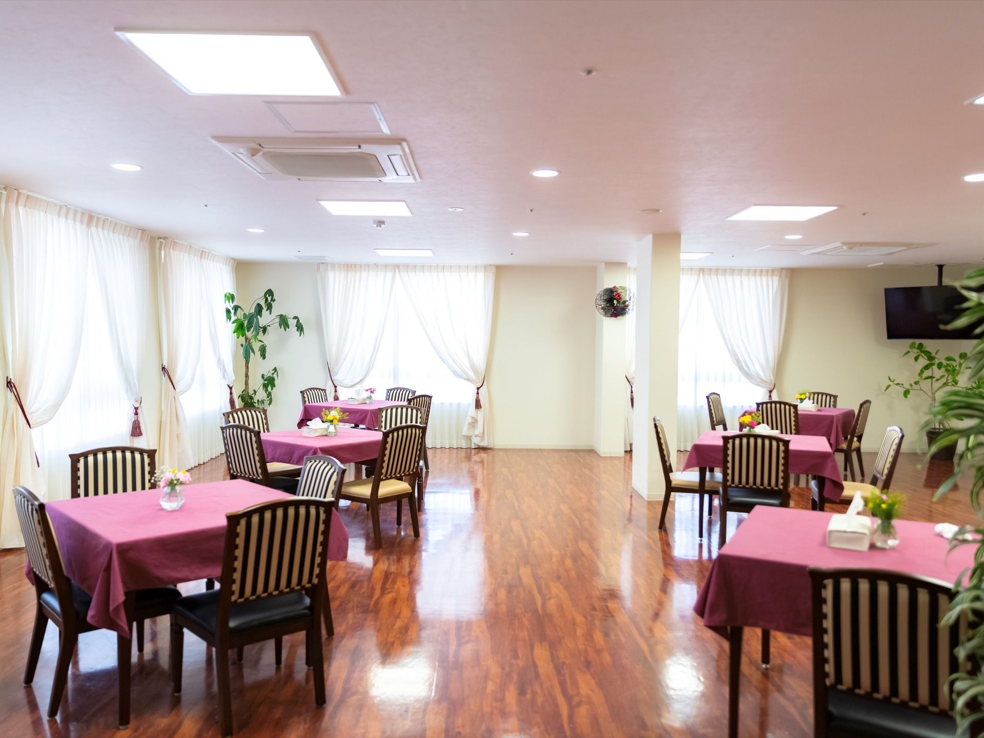 食堂には、紫系統の色のテーブルクロスがかかったテーブルと、洋風の椅子が多く置かれている。レースカーテンがかかっている。