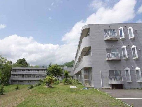 周囲に芝生や樹木がたくさんあり、緑豊かな敷地内に建つ施設