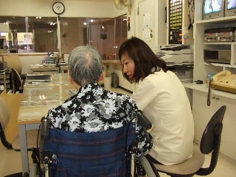 事務室で、スタッフと会話をしている車椅子に座っている入居者