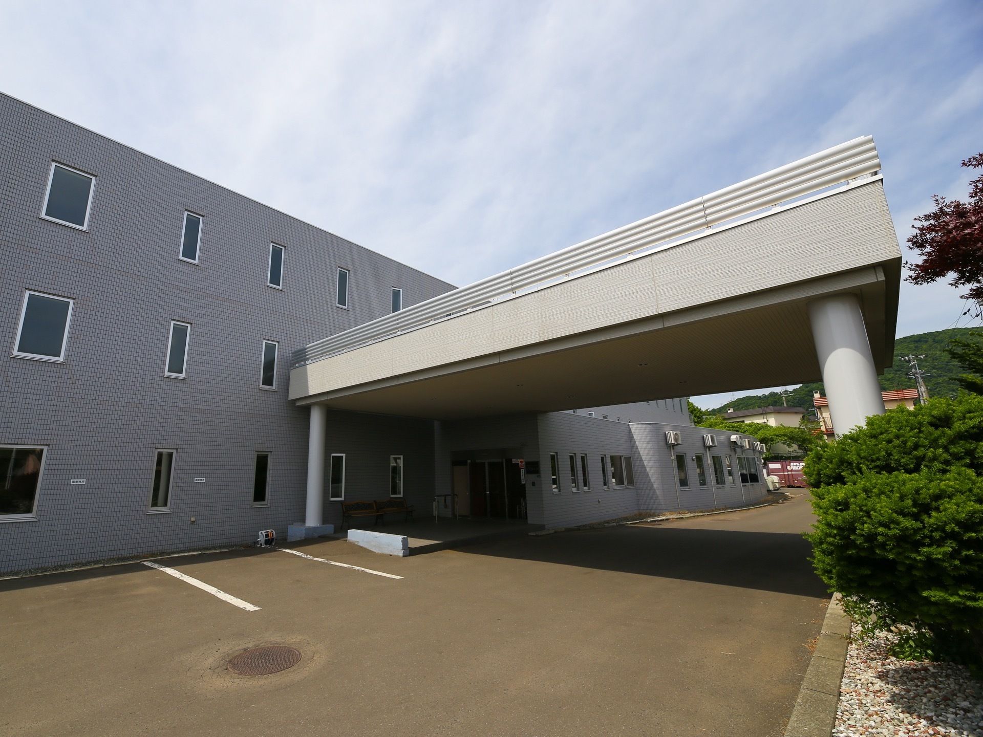 玄関の前には、大きな屋根がかかっている。建物の周囲は、アスファルトで舗装されており、広々としている。