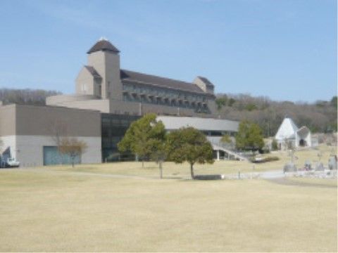 ブラウンを基調とした大きな建物と、目の前に広がる青い芝生