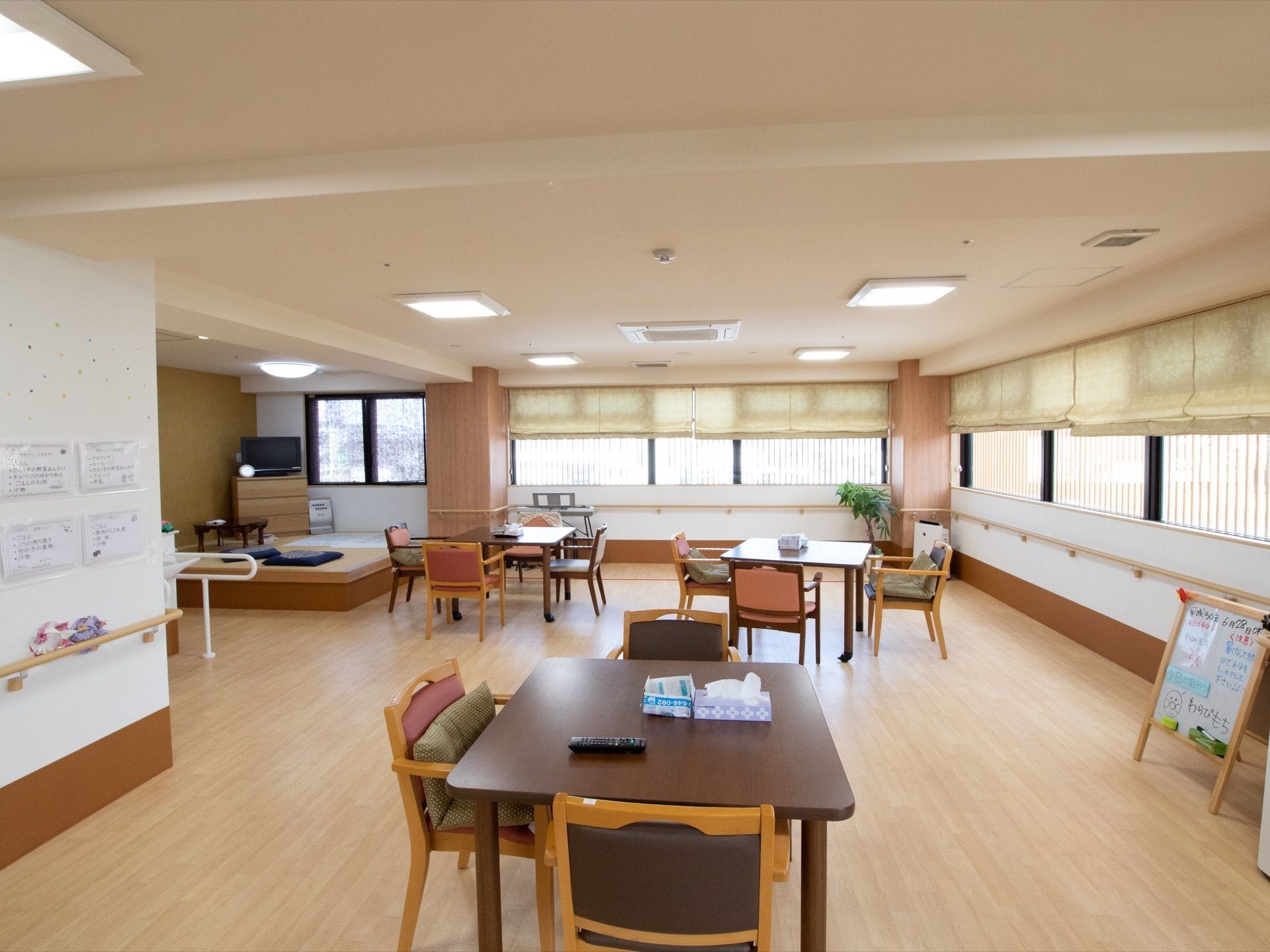 フローリングと畳敷きの２つの空間に分かれた部屋である。テーブルと椅子が複数置かれている。壁には手すりが取り付けてある。