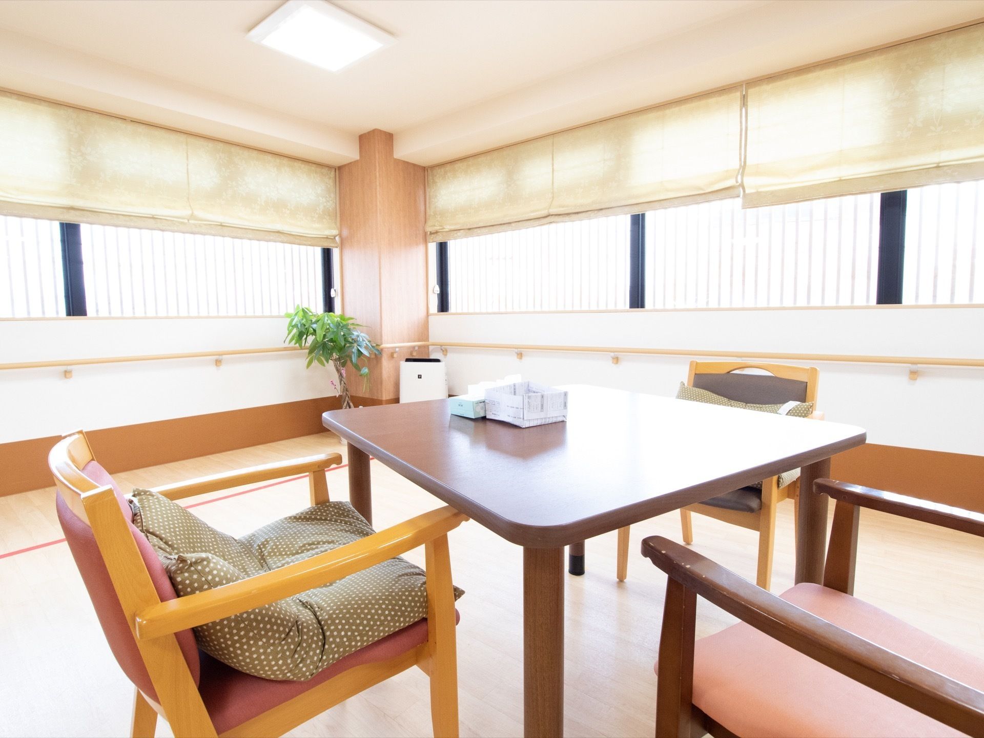 格子窓に囲まれたフロアである。観葉植物がある。テーブルと椅子が置かれている。壁面には手すりが取り付けられている。