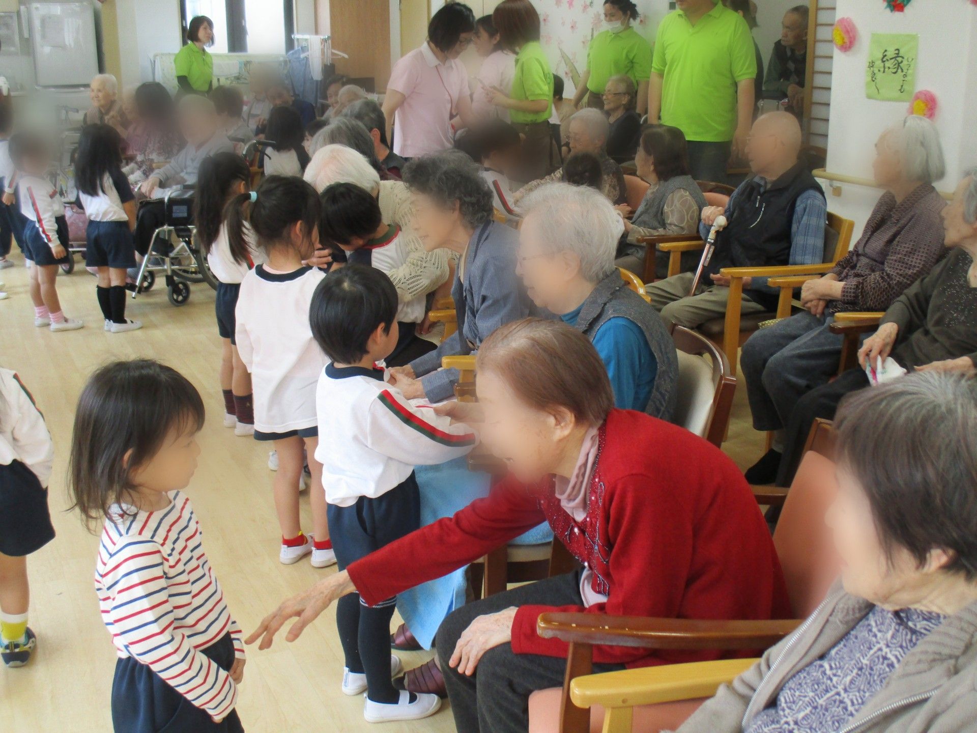 ステージで歌う女性たちのコーラスを聴いている入居者様たち