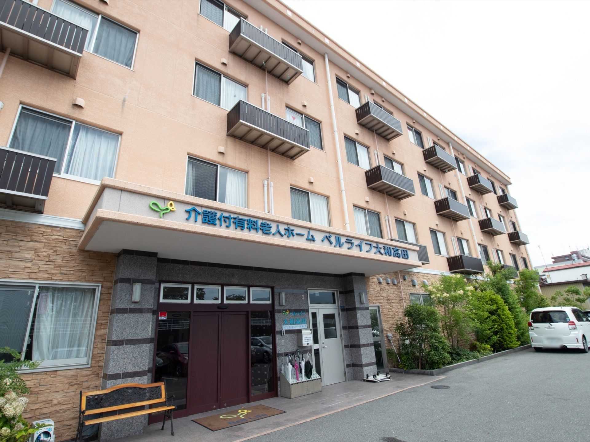 玄関前は広くバリアフリー設計になっている。扉の近くには一息つけるようベンチが置かれている。傘立てもある。