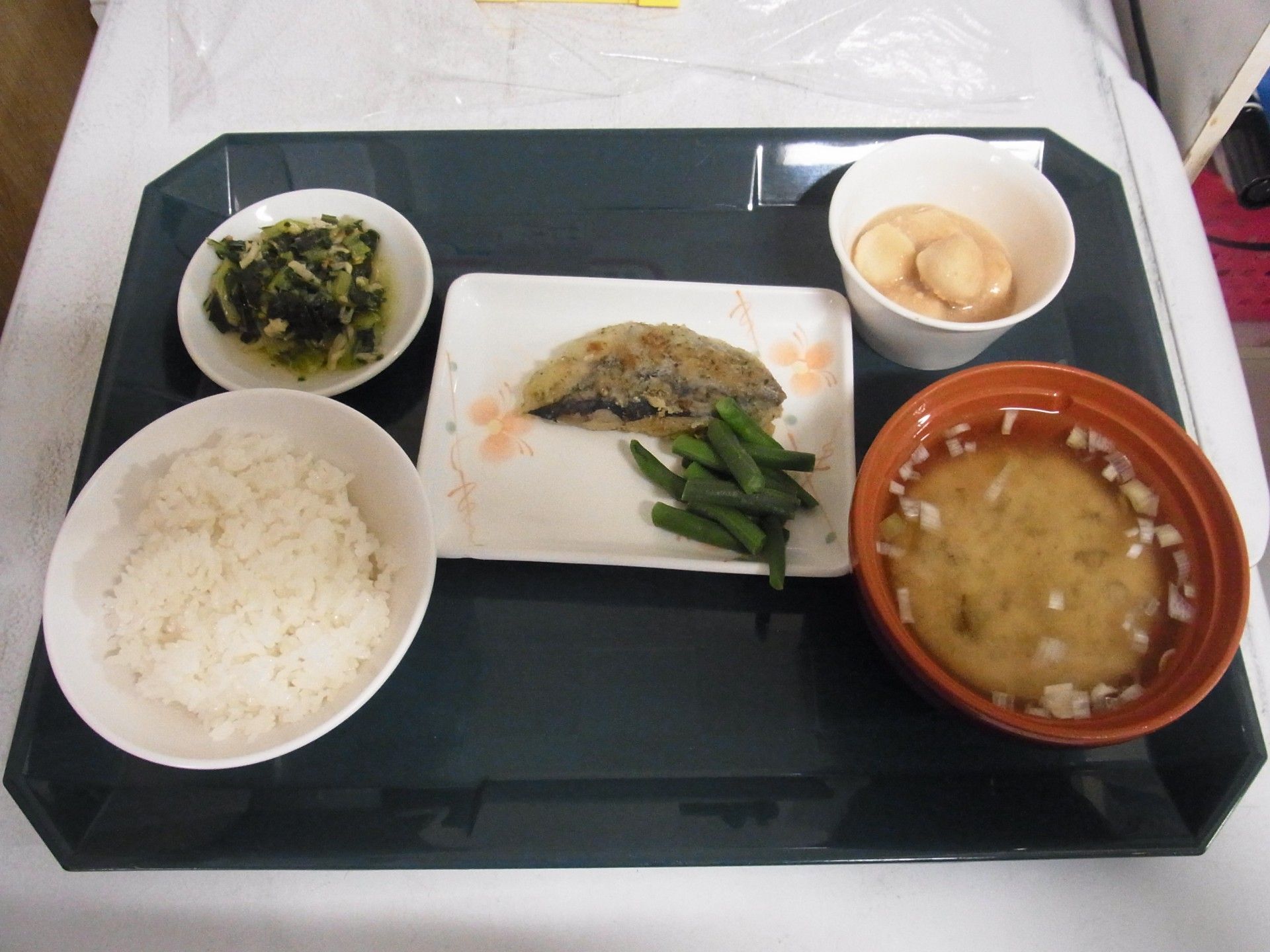 トレーの上に用意された一人分の食事である。メイン料理は魚である。さらにご飯とみそ汁、小鉢が2品用意されている。